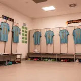Szczecińska Pogoń gotowa do meczu z Cracovią. Koszulki zawodników wiszą w szatni, obok piłka i buty.