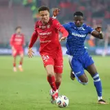 Piłkarze Widzewa Łódź i Lecha Poznań walczą o piłkę na boisku. Intensywny przebieg meczu.