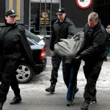 Ochroniarze w czarnych kurtkach i czapkach wyprowadzają mężczyznę owiniętego w koc. Może to być interwencja wobec kiboli.