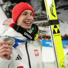 Uśmiechnięty skoczek narciarski w czerwonej czapce trzyma srebrny medal. Polacy na Igrzyskach 2026 z pewnością będą walczyć o kolejne laury!