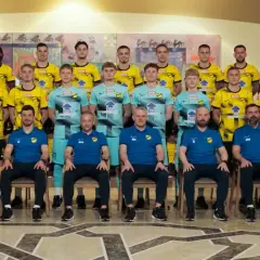 Drużyna piłkarska Wieczysta Kraków w komplecie. Zawodnicy i sztab szkoleniowy pozują do wspólnego zdjęcia w strojach klubowych.
