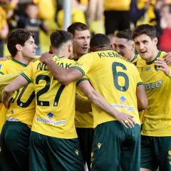 Piłkarze Górnika Zabrze świętują zwycięstwo nad Koroną Kielce. Drużyna w żółtych koszulkach z numerami 27 i 6 cieszy się z sukcesu.