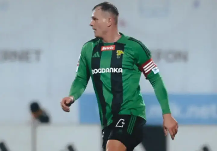 Piłkarz Górnika Łęczna w zielonej koszulce z czarnymi pasami, gotowy do gry przeciwko GKS Tychy.