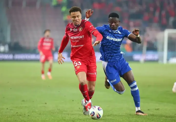 Piłkarze Widzewa Łódź i Lecha Poznań walczą o piłkę na boisku. Intensywny przebieg meczu.