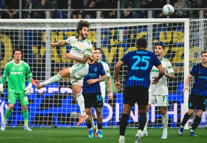 Piłkarz w białej koszulce Inter Mediolan wyskakuje do strzału głową, podczas gdy zawodnik AS Roma z numerem 25 próbuje go zatrzymać.