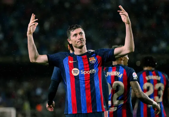 Robert Lewandowski, król strzelców, w koszulce Barcelony z podniesionymi rękami, świętuje zwycięstwo.