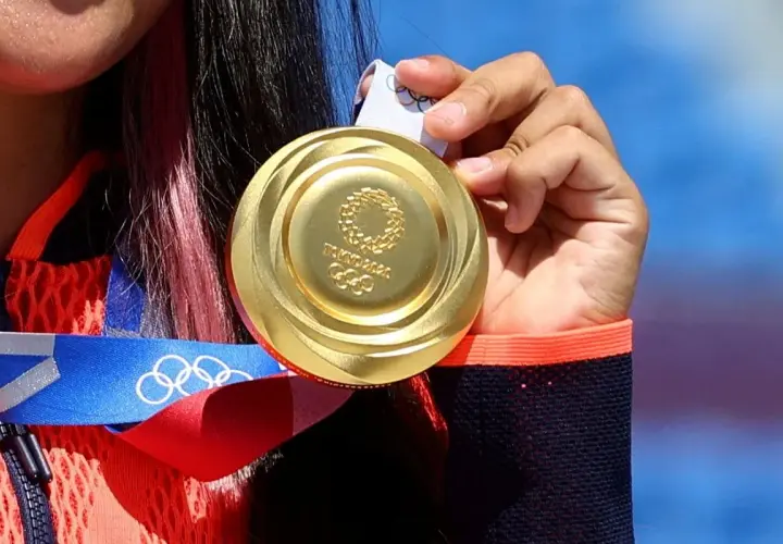 Złote medale olimpijskie z Tokio 2020, symbol ciężkiej pracy i zwycięstwa, błyszczą w dłoniach sportsmenki.