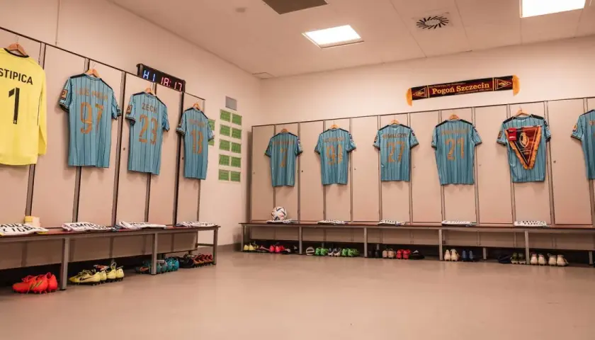 Szczecińska Pogoń gotowa do meczu z Cracovią. Koszulki zawodników wiszą w szatni, obok piłka i buty.