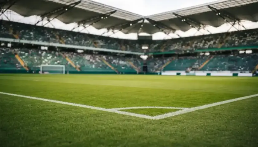 Piłkarskie **baraze** na pustym stadionie, zielona murawa i trybuny czekające na kibiców.