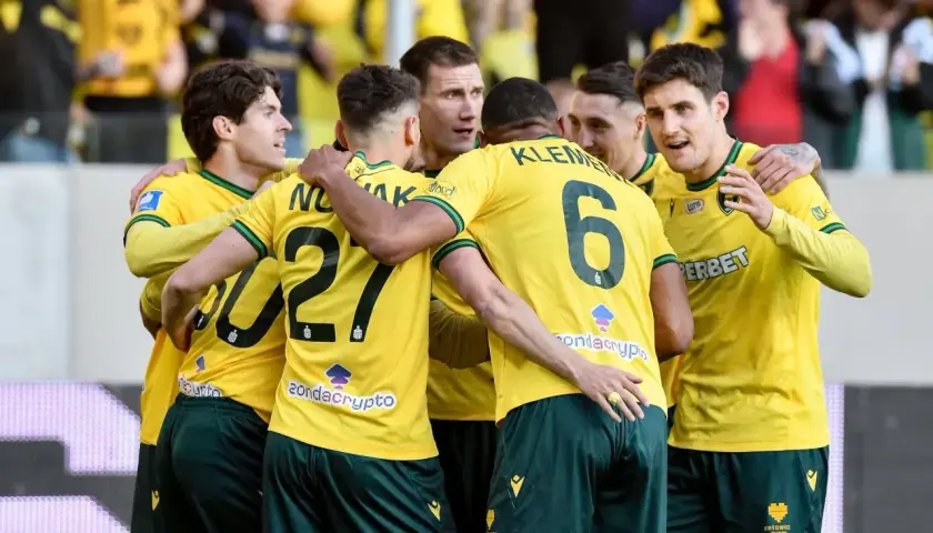Piłkarze Górnika Zabrze świętują zwycięstwo nad Koroną Kielce. Drużyna w żółtych koszulkach z numerami 27 i 6 cieszy się z sukcesu.