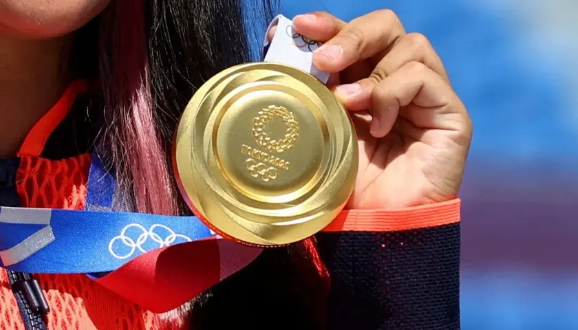 Złote medale olimpijskie z Tokio 2020, symbol ciężkiej pracy i zwycięstwa, błyszczą w dłoniach sportsmenki.