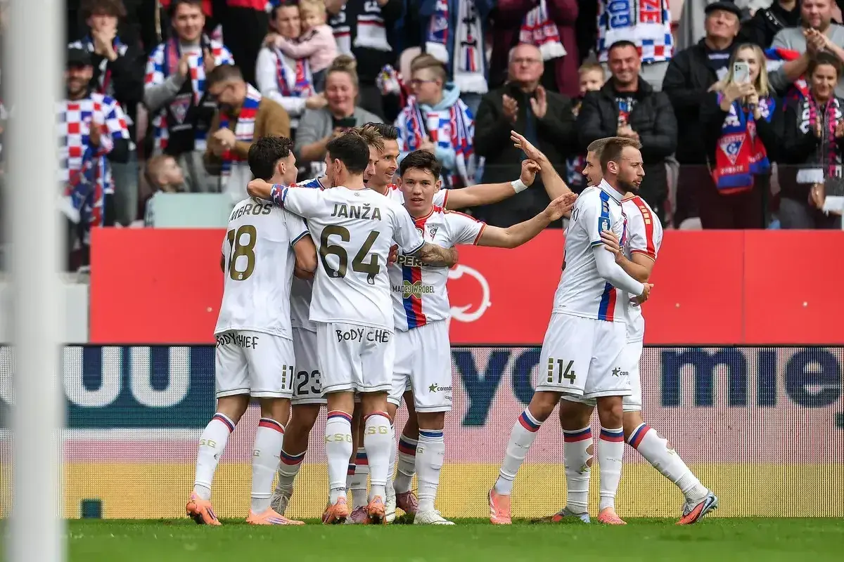 Piłkarze Górnika Zabrze w białych strojach świętują bramkę, w tle kibice.