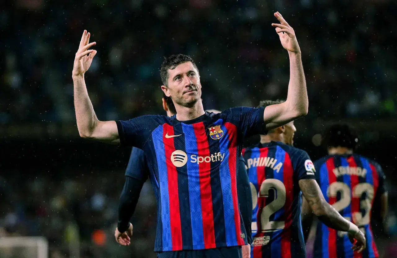 Robert Lewandowski, król strzelców, w koszulce Barcelony z podniesionymi rękami, świętuje zwycięstwo.