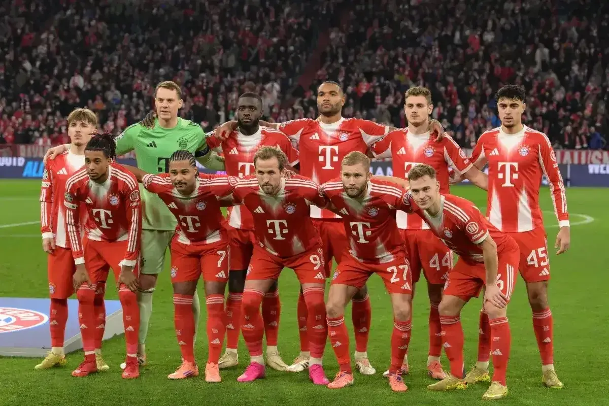Drużyna Bayernu Monachium, znana z występów w **Bundeslidze**, prezentuje się w czerwono-białych strojach. Zawodnicy stoją gotowi do gry.