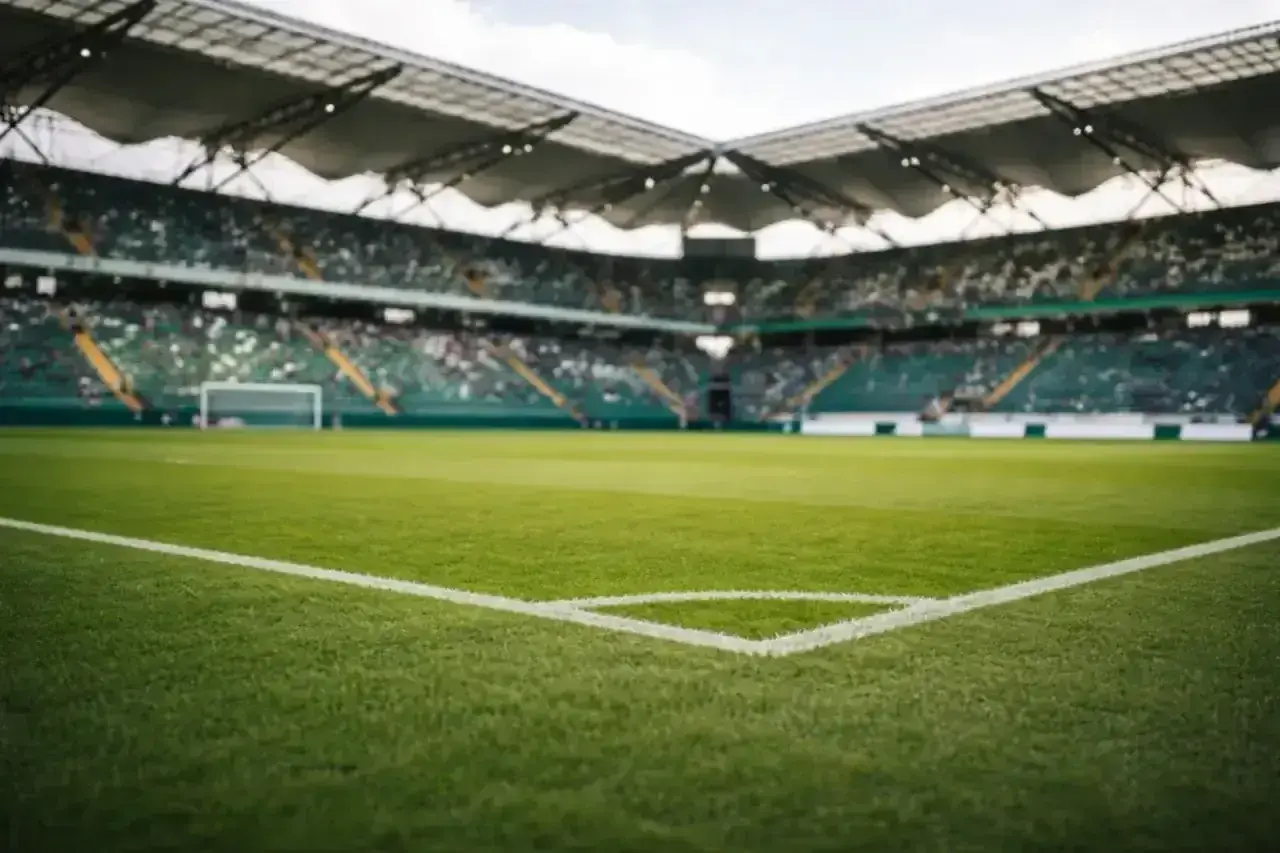 Piłkarskie **baraze** na pustym stadionie, zielona murawa i trybuny czekające na kibiców.
