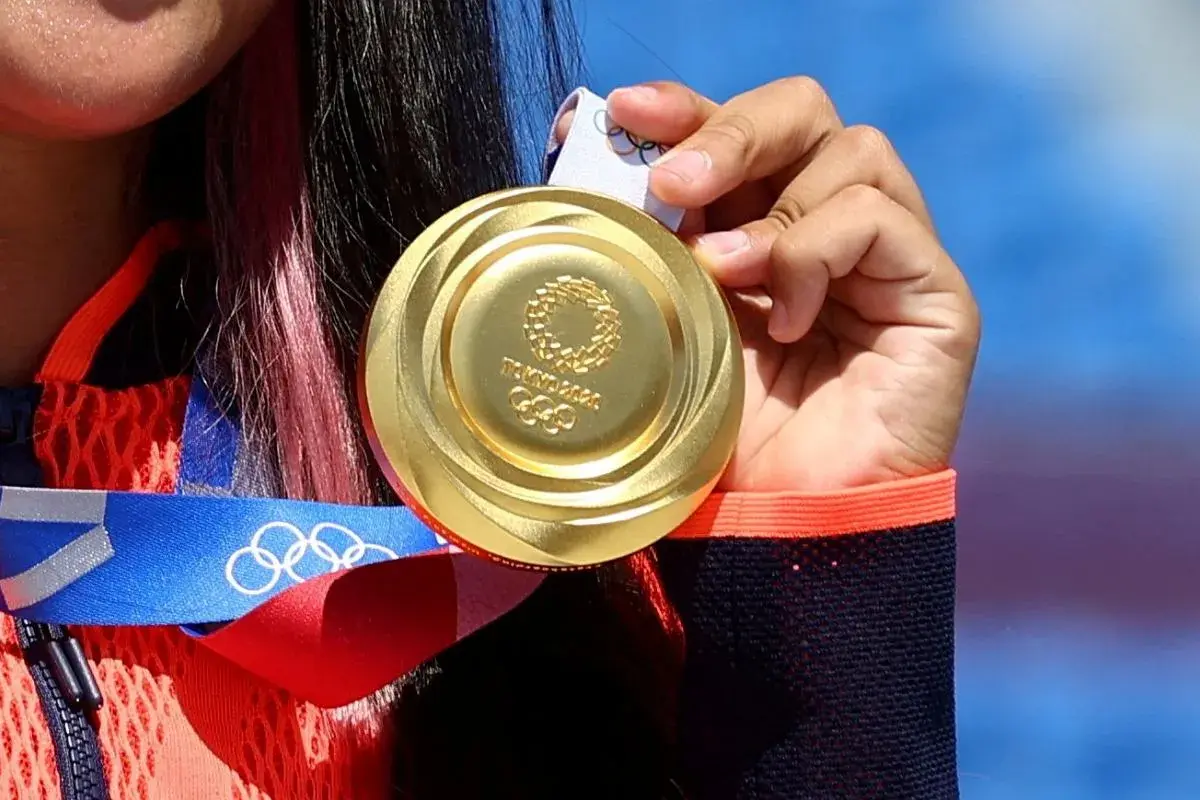 Złote medale olimpijskie z Tokio 2020, symbol ciężkiej pracy i zwycięstwa, błyszczą w dłoniach sportsmenki.