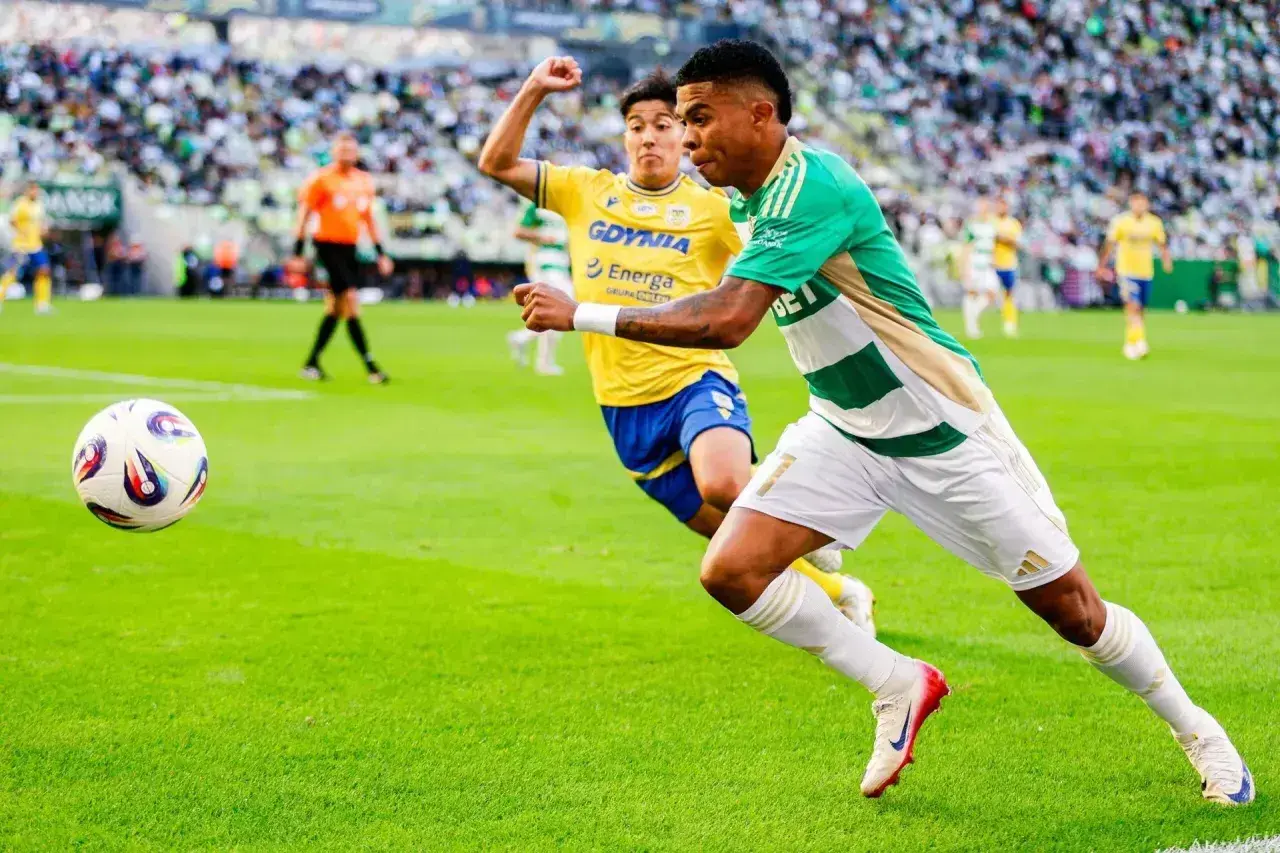 Piłkarz Lechii Gdańsk w akcji przeciwko Arce Gdynia. Piłka w grze na zielonej murawie stadionu.