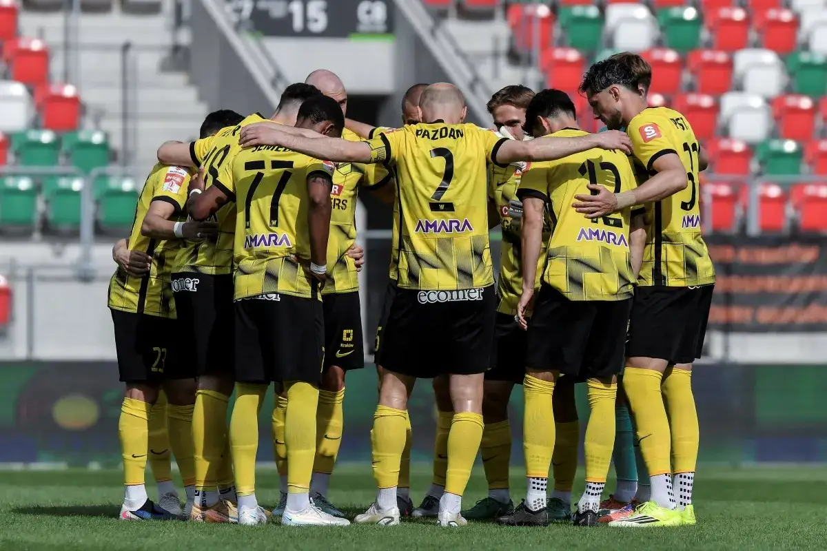 Wieczysta Kraków – zawodnicy w żółtych strojach tworzą zgraną grupę na boisku.