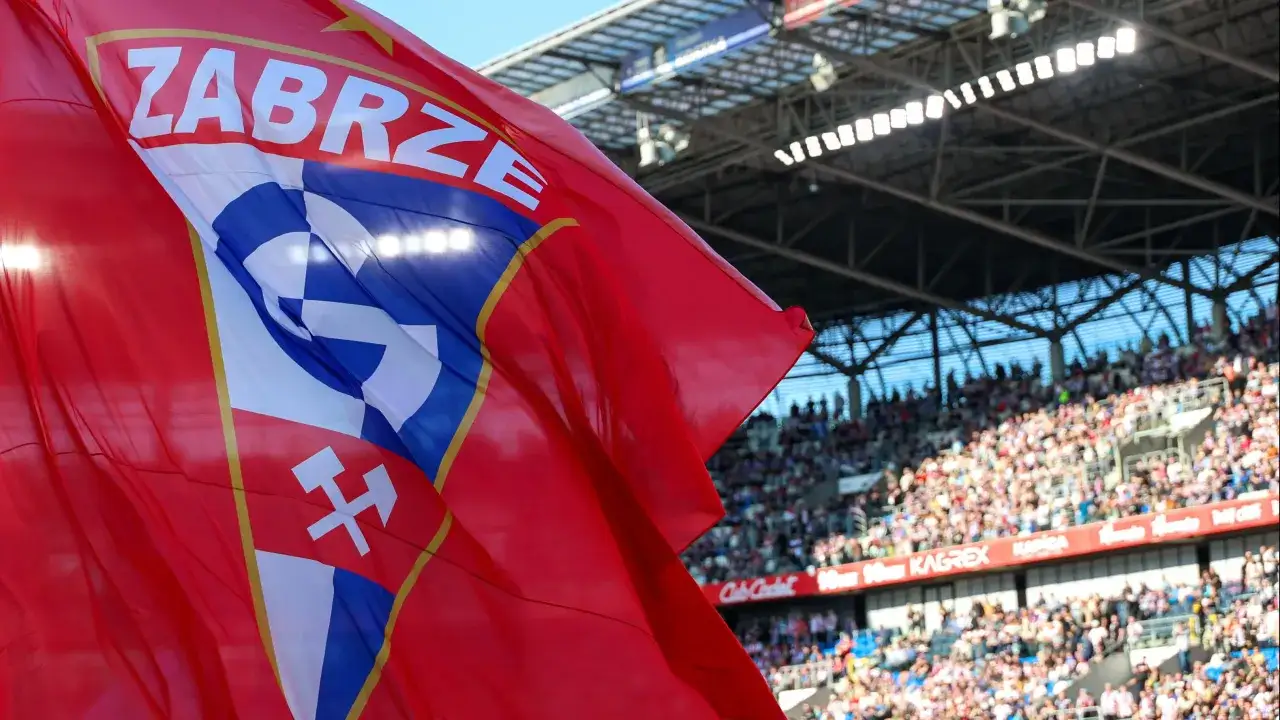 Czerwona flaga z herbem Górnika Zabrze powiewa na tle trybun pełnych kibiców. Emocje przed meczem Górnik Zabrze – Korona Kielce sięgają zenitu.