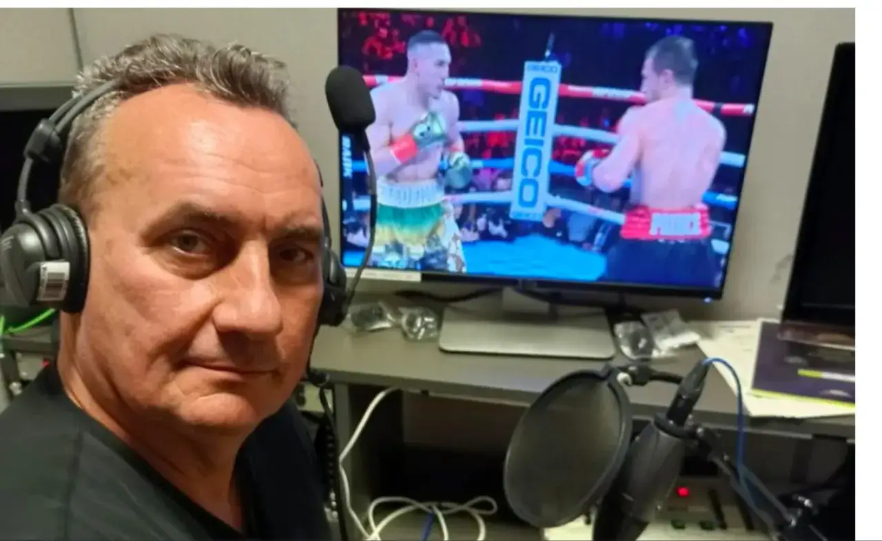 Komentator sportowy w słuchawkach przed monitorem z walką bokserską, gotowy do relacji.